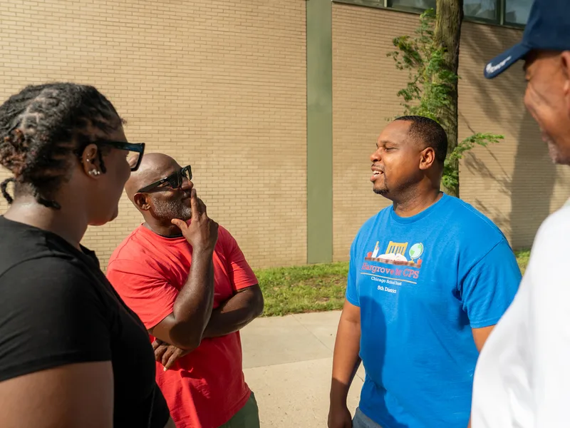Anthony Hargrove conversando con adultos junto a unos árboles al aire libre.