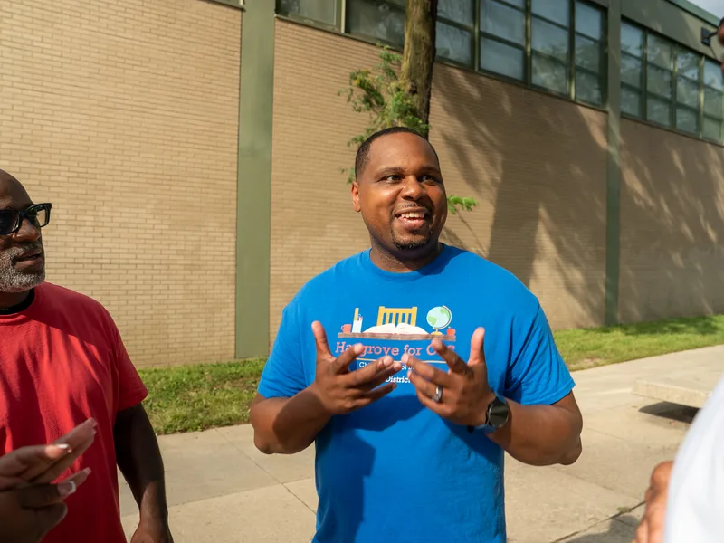 Anthony Hargrove gesticulando mientras conversa con adultos al aire libre.