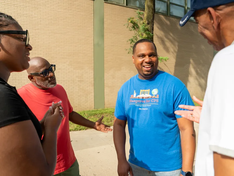 Anthony Hargrove sonriendo mientras conversa con un grupo de adultos al aire libre.