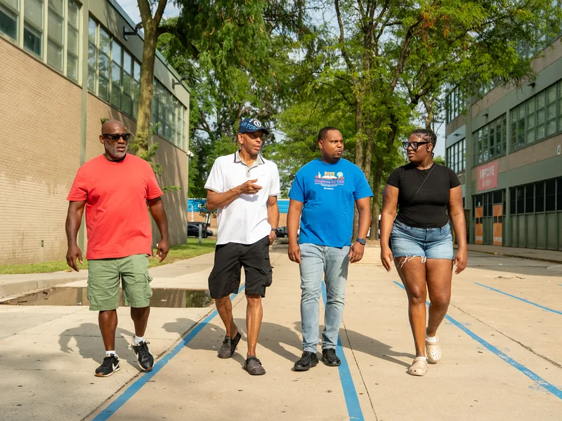 Anthony Hargrove caminando con adultos por una acera junto a una escuela.