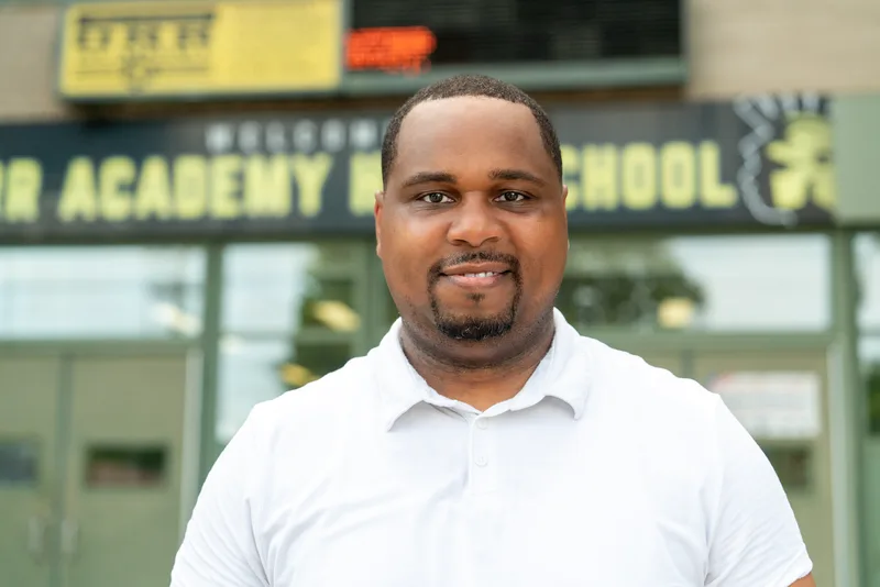 Anthony Hargrove con un polo blanco y el letrero de una escuela al fondo.