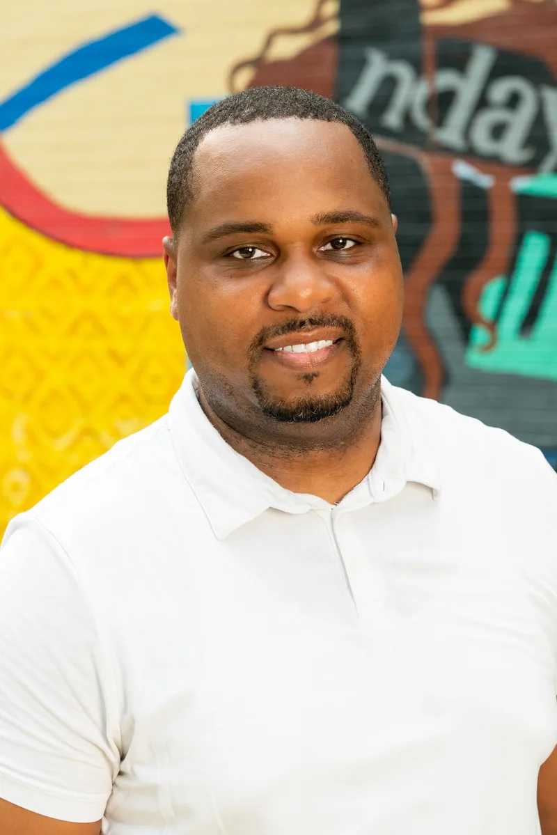 Retrato vertical cercano de Anthony Hargrove con un polo blanco junto a un mural.