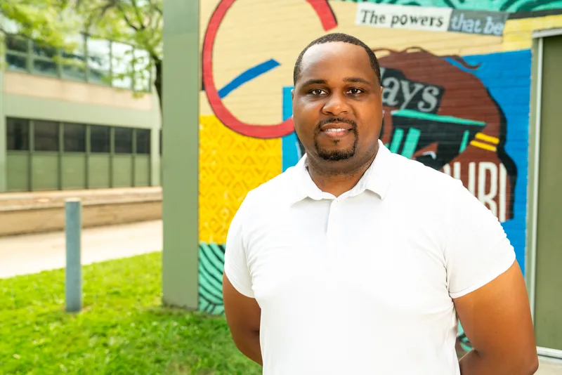 Anthony Hargrove con un polo blanco y las manos detrás de la espalda frente a un mural.