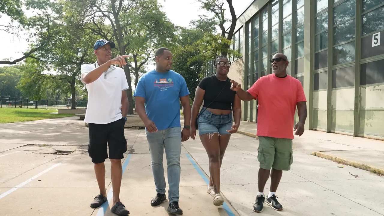 Anthony Hargrove caminando con tres adultos junto a una escuela.